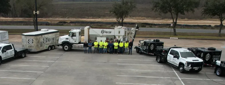 Workers posing with trucks and trailers on road.