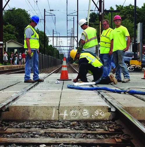 Workers inspecting railroad tracks at a station.