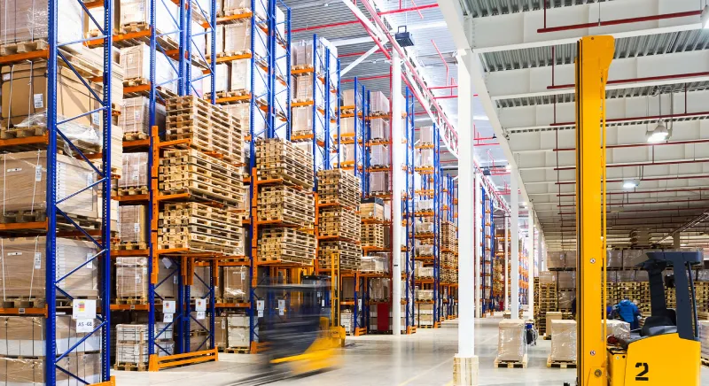 Busy warehouse with forklifts and stacked goods.