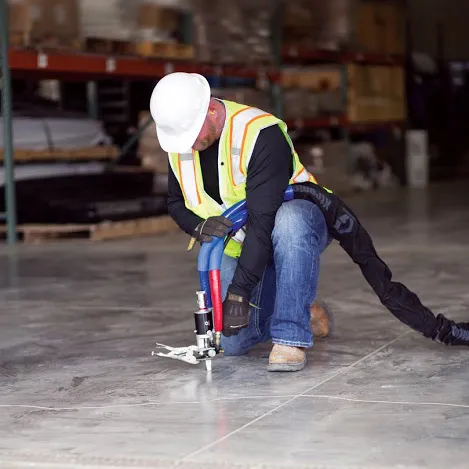 Worker using tool on warehouse floor.