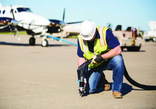 Worker inspecting equipment on airport tarmac.