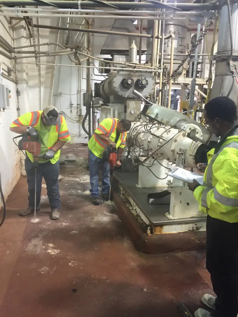 Workers maintaining industrial machinery in factory.