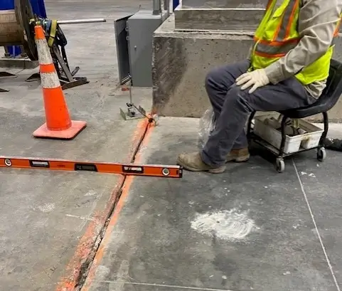 Worker using level on concrete floor at construction site.