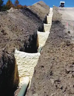 Deep trench with pipeline installation in progress.