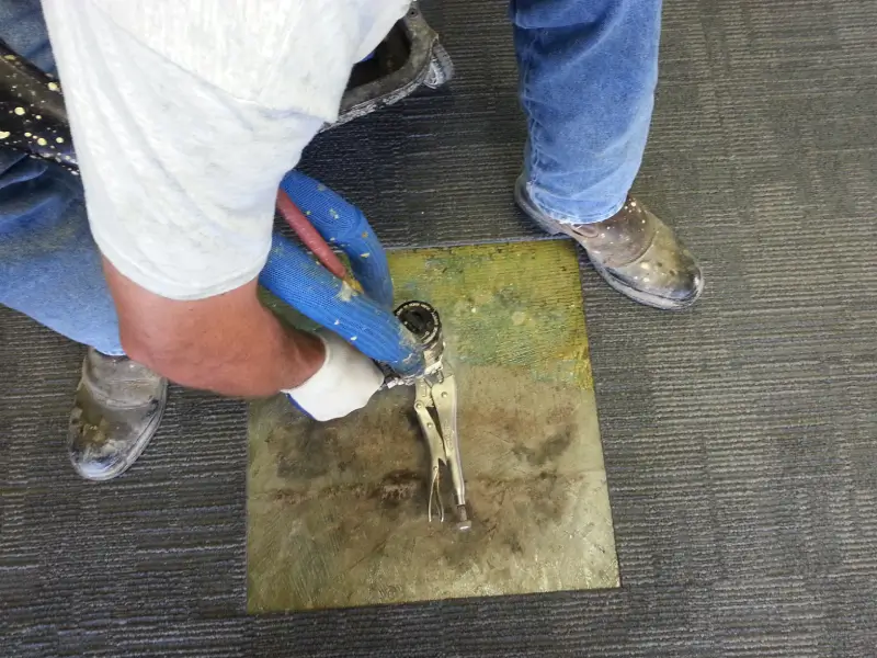 Worker applying caulking gun on floor joint.