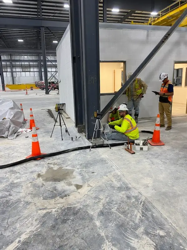 Construction workers installing equipment in industrial warehouse.