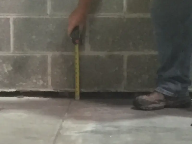 Worker measuring gap between pavement slabs.