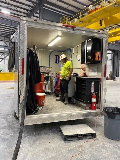 Worker in industrial facility using mobile workshop setup.