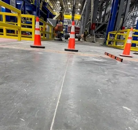 Industrial warehouse floor with traffic cones and machinery.