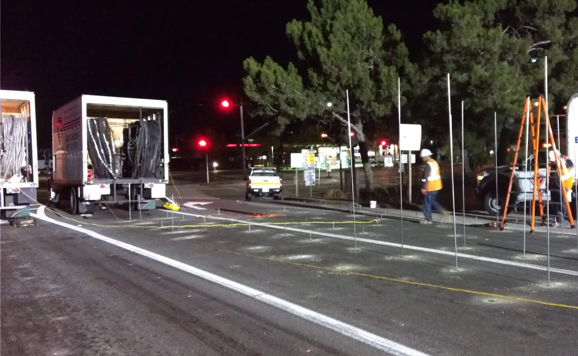 Nighttime roadwork with workers and equipment near intersection.