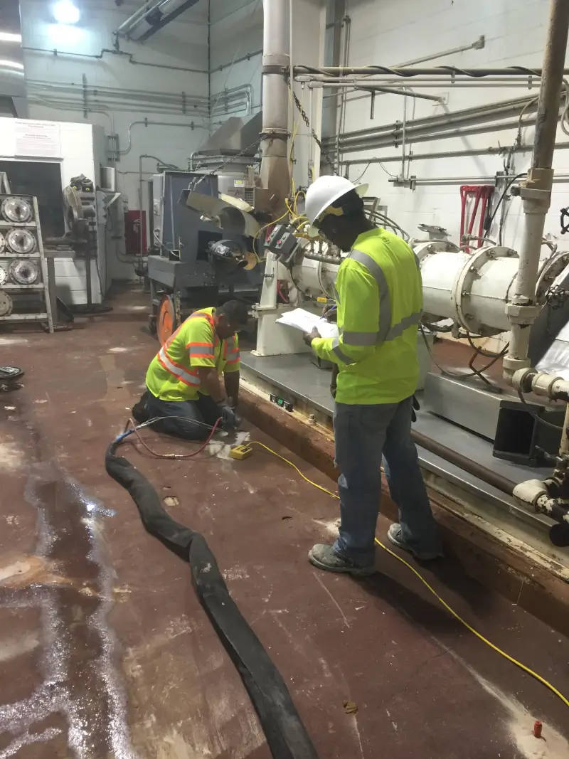 Workers inspecting machinery in industrial facility.