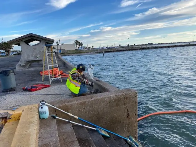 Worker repairing pier by the sea at sunset.