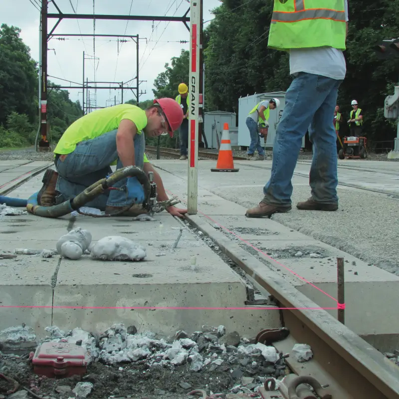 Workers repairing railway tracks outdoors.